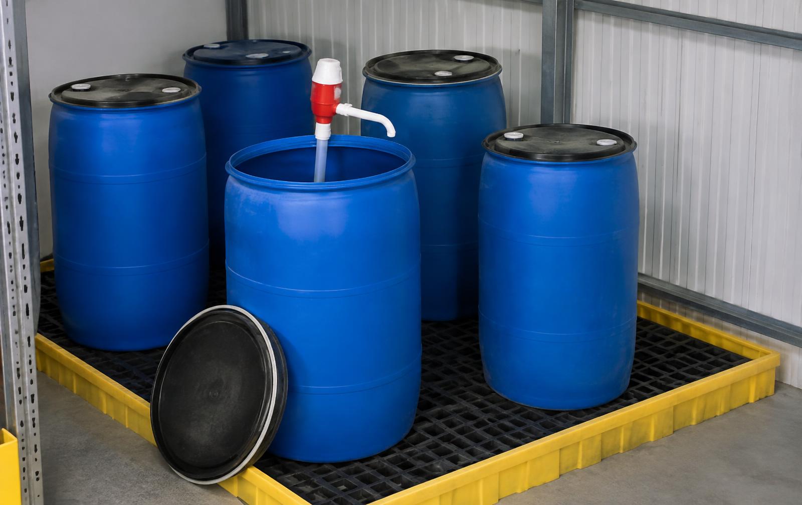 Blue plastic fuel barrels on a bunded spill pallet inside a storage bay